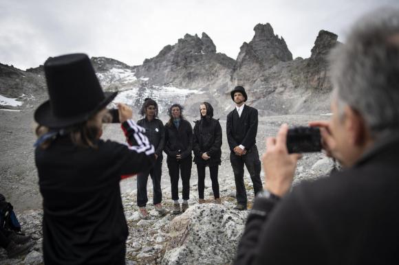 Grupo de gente vestida de negro en sesión fotográfica, en un terreno desértico en la montaña