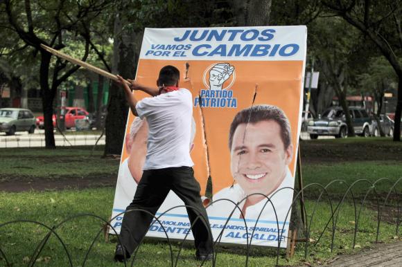 Un homme se prépare à détruire à la hache une affiche électorale de Alejandro Sinibaldi Aparicio, ancien ministre du Guatemala