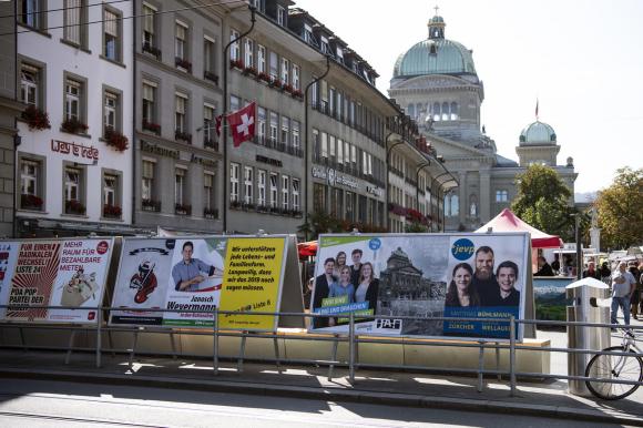 Manifesti di propaganda elettorale su una piazza e sullo sfondo il Palazzo federale a Berna
