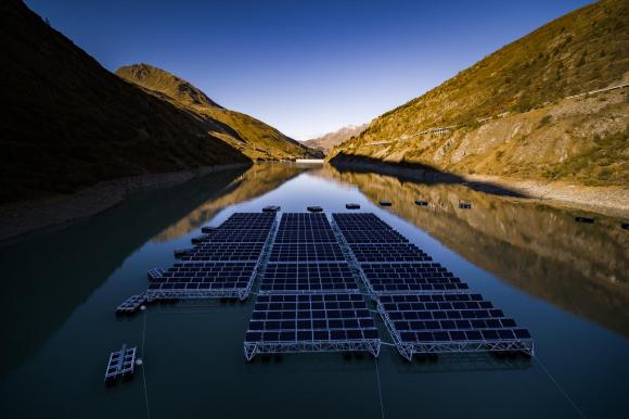 Immagine di un lago di montagna ritratto al mattino, con pannelli solari appoggiati sul filo dell acqua