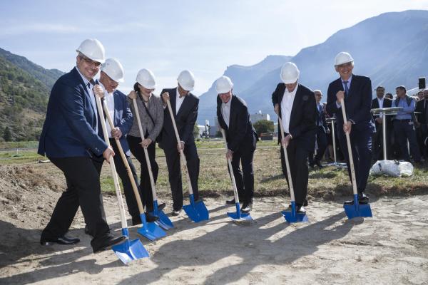 Business people in suits and hard hats break the soil with shovels
