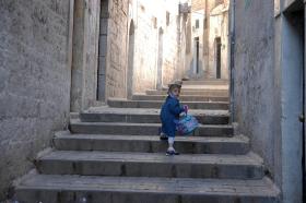 Young girl looks over shoulder as she walks up steps in alley