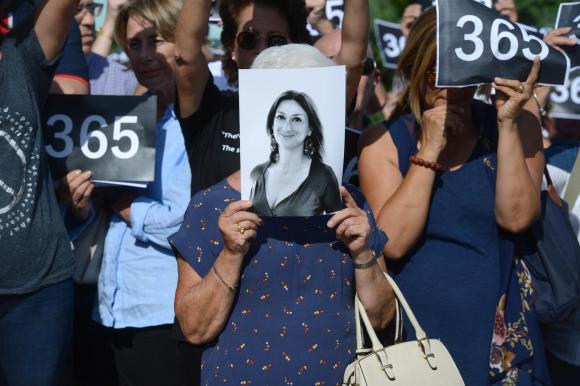 Demonstrierende Frauen halten ein Bild einer Frau und Nummernschilder in den Händen.