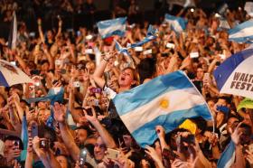 Una muchedumbre exultante agita banderas argentinas.