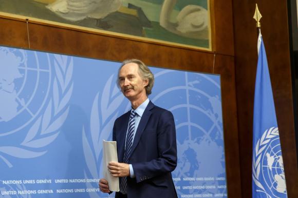 رجل يمسك بيده أوراقا ويقف أمام علم الأمم المتحدة