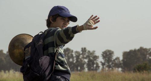 Un niño hace una señal de despedida con la mano