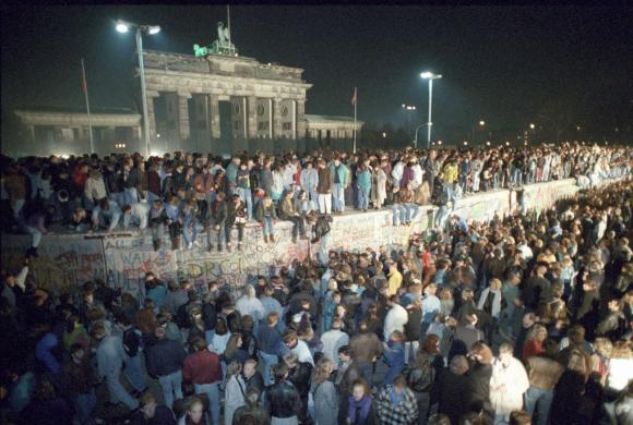 In der Nach vom 9. auf den 10. November 1989 klettern Hunderte von Menschen über die Berliner Mauer vor dem Brandenburger Tor. 