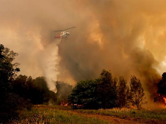 Hélicoptère lâchant de l eau sur un feu de forêt.