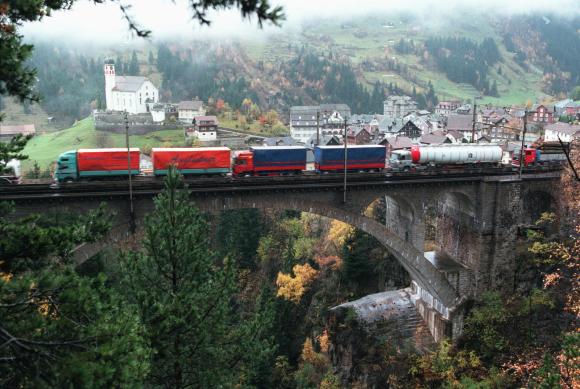Train with trucks passing a bridge in the Swiss mountains