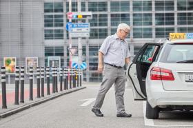 Elderly man opening taxi car door