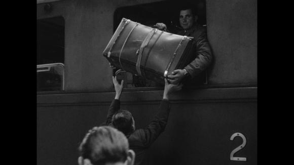uomo scarica una valigia da un finestrino di un treno
