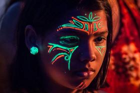 Una niña con la cara pintada con pintura fluorescente
