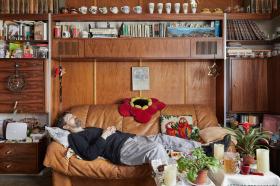 Mann schläft auf Sofa vor Wohnwand