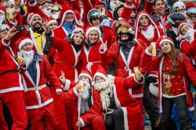 رجال ونساء يرتدون ملابس بابا نويل الحمراء والموشحة بالأبيض