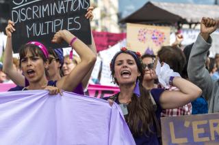 Mujeres manifestándose con pancartas y el brazo en alto