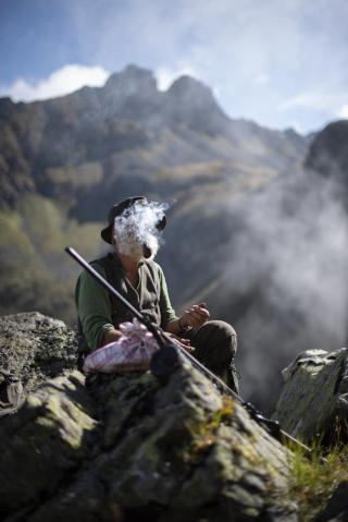 Un hombre fuma sentado en medio de un paisaje montañoso