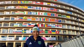 Jovem em frente à Vila Olímpica coberta de bandeiras