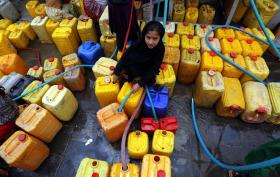 Ein Mädchen sitzt auf gelben Wasserkanistern.