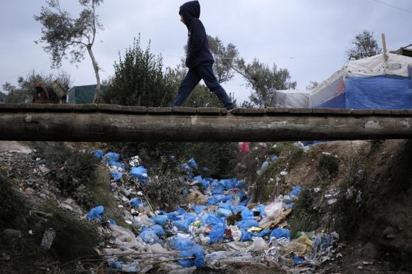 A migrant boy walks over discarded garbage outside the Moria refugee camp