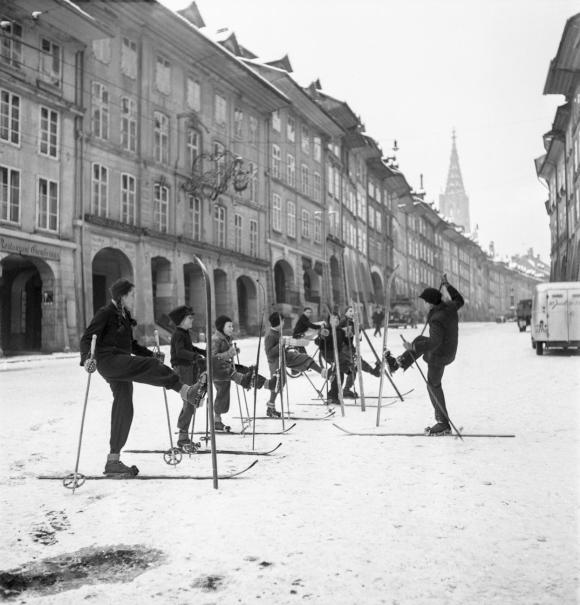 Children in the old town of Bern do warm-up exercises on their skis