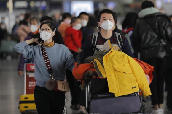 1月26日北京首都國際機場3號航站樓內戴著口罩的乘客。鑑於目前的情況，中國要求旅行社暫停所有國內外團體旅遊業務。