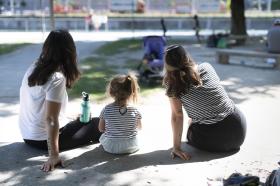 Dos jóvenes mujeres y una niña de espaldas sentadas en el suelo