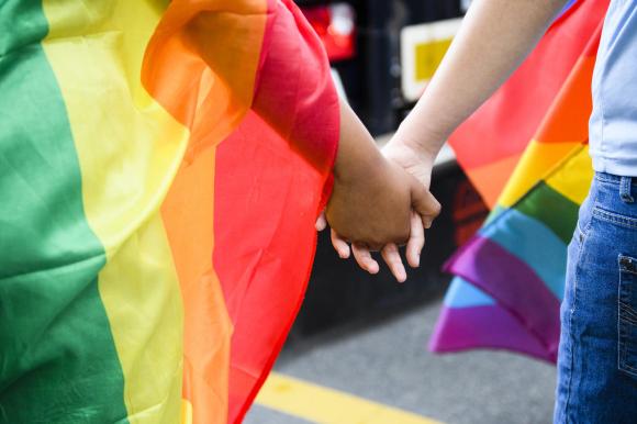 two people with rainbow flags holding hands.