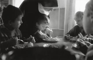 Children eating food with a nun.