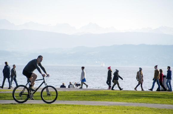 People enjoy walking and cycling along Lake Zurich on a mild and sunny winter s day