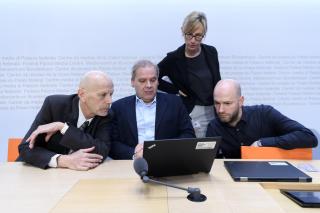 tre uomini e una donna guardano lo schermo di un computer portatile