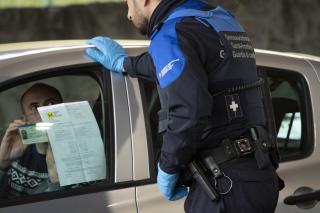 شرطي سويسري يراقب فرنسي يعبر الحدود بين البلديْن