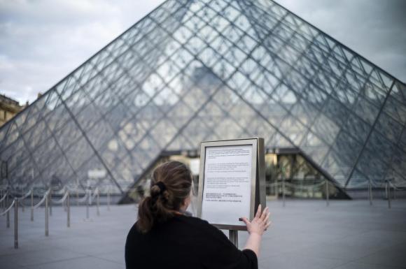 Persona davanti alla piramide del Louvre.