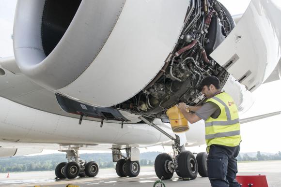 A maintenance worker works on an airplane engine