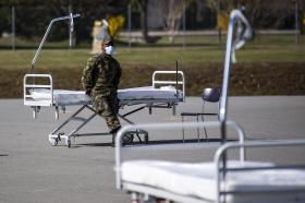 Soldado con cubreboca junto a una camilla de hospital al aire libre