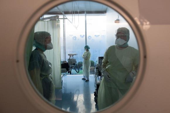 medici e infermieri in camice e dietro a un vetro a forma di oblò