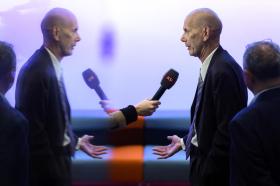Bald man in suit speaking into microphone