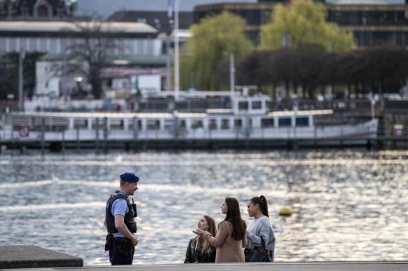 un poliziotto parla a tre ragazze in riva al lago.