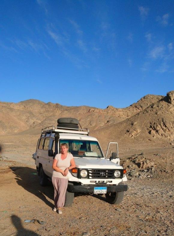 Femme à côté d une jeep dans le désert.
