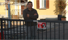 un uomo appoggiato a un cancello del giardino di una casa.