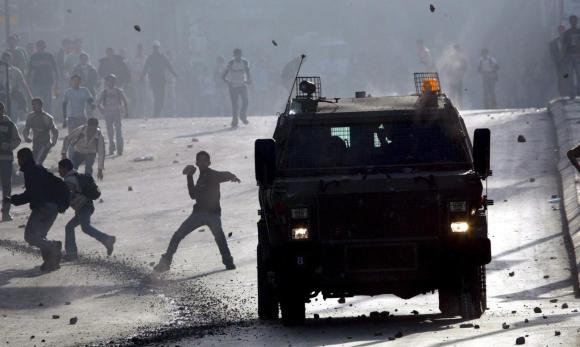 شبان فلسطينيون يرجمون عربة عسكرية بالحجارة