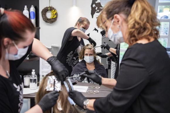 Coiffeur und Kundin beim Haareschneiden - mit Hygienemaske