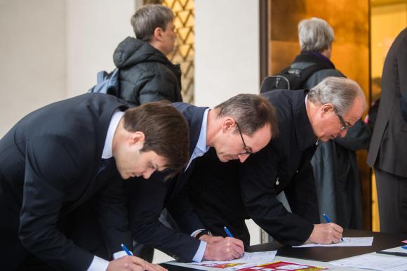 Three men signing documents