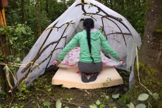 Une femme entre dans une tente dans un bois