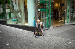 Un homme mendie par terre dans la rue