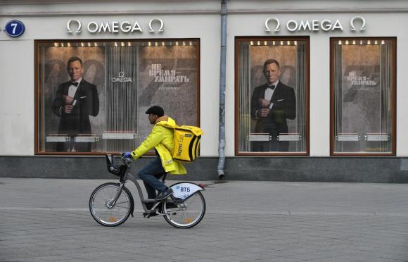 رجل على دراجة يمر أمام متجر لبيع الساعات مغلق