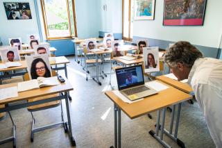 4月29日，克里斯托弗·布兰克(Christophe Blanc)老师在私立学校“ Ecole Ardevaz”的学生照片前上经济学课。