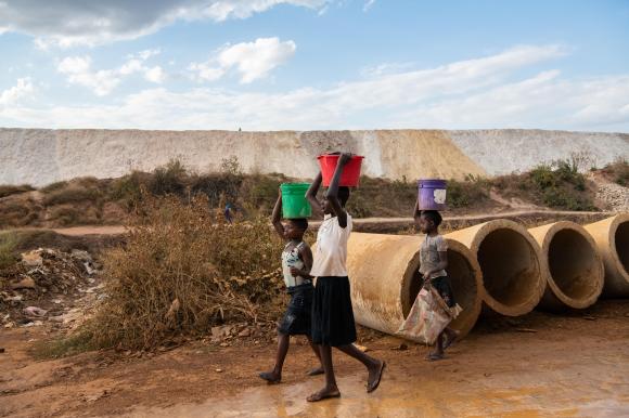 Children walk past copper mine