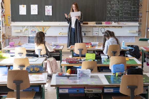 Una maestra con due bambini a scuola, figli di genitori che non possono tenere a casa i bimbi.