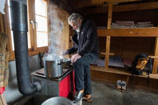 An alpinist prepares dinner in the old Fridolin mountain hut.