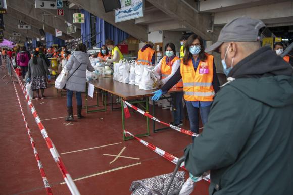 رجال ونساء في صفوف ينتظرون توزيع مساعدات غذائية في جنيف